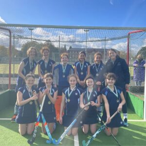 Girls holding hockey sticks in front of a net