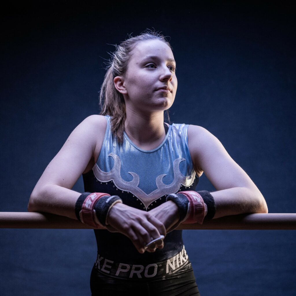 Student leaning over a railing in a gymnastics leotard