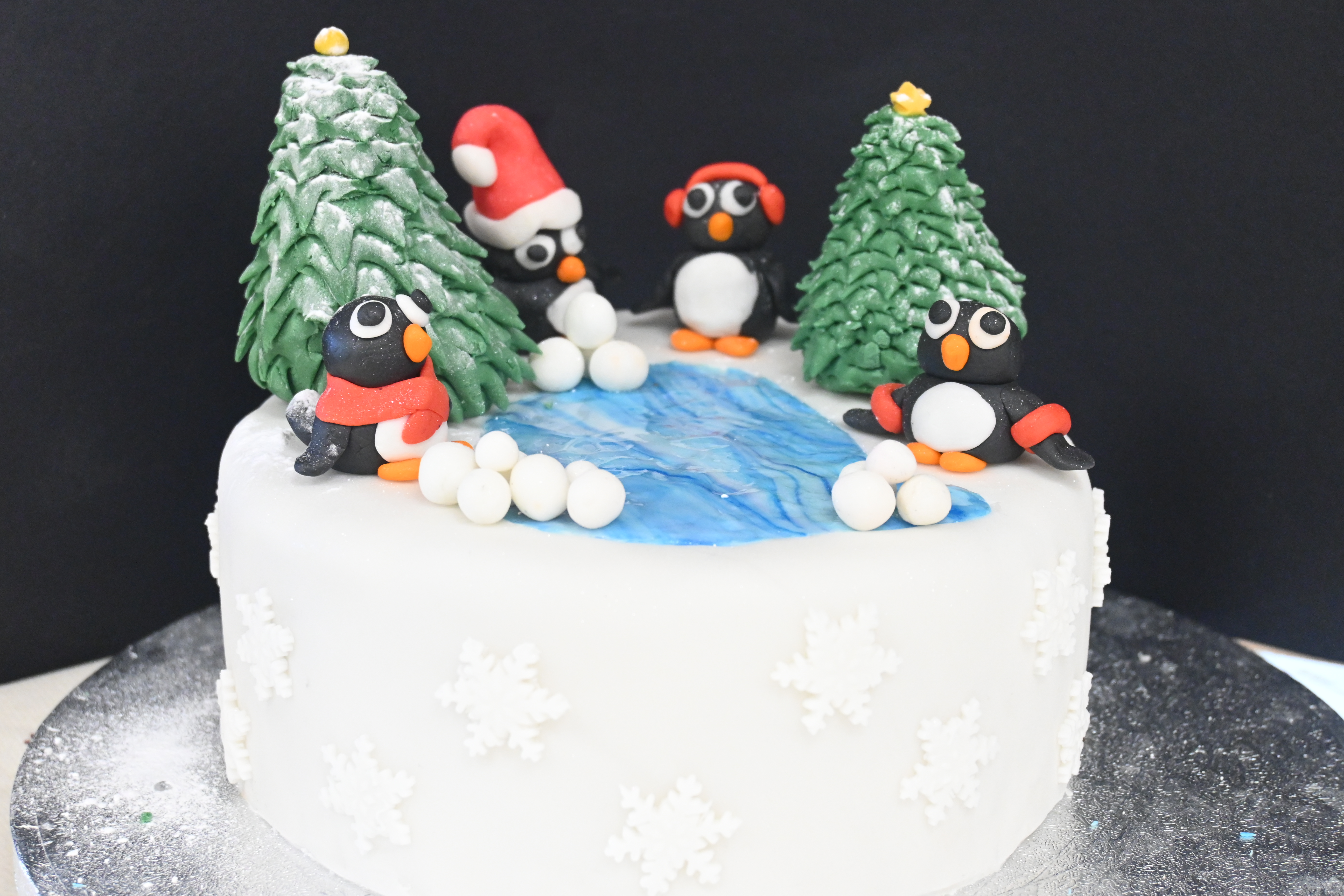 Cake topped with penguins, trees and snowballs