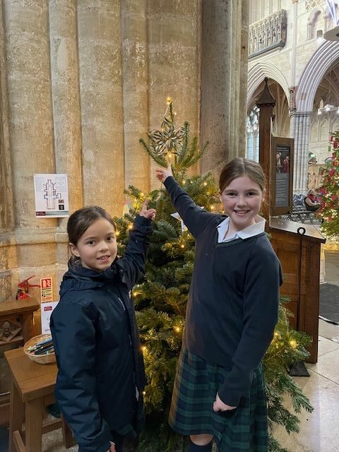 Two girls pointing to a star on a Christmas Tree